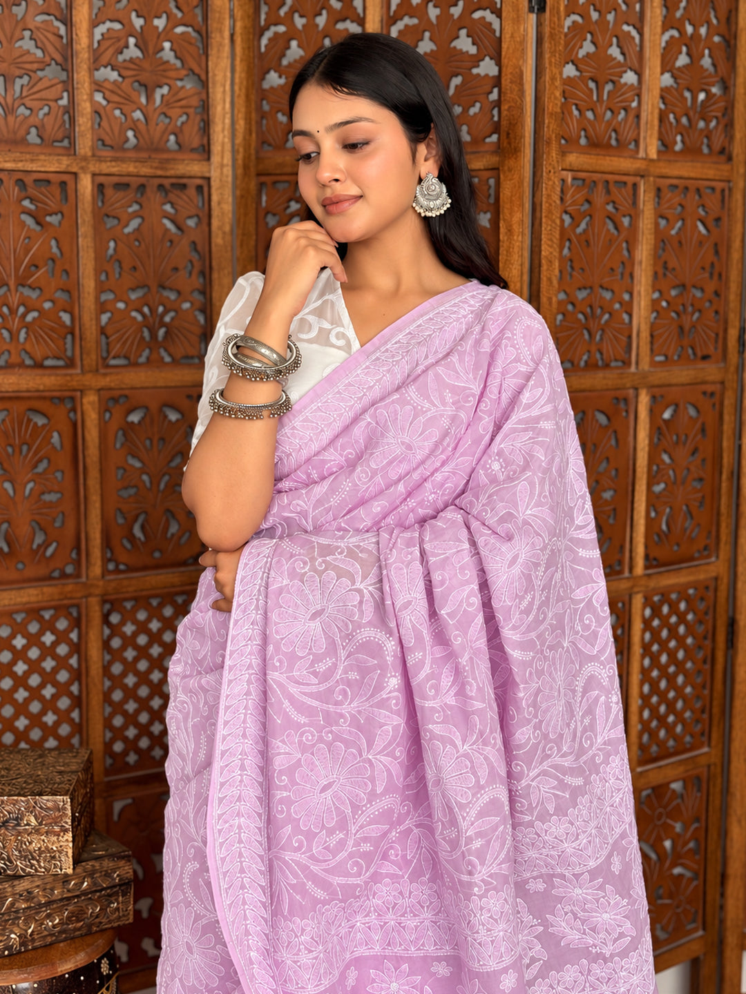 Adhira Cotton Chikankari Saree styled with a short-sleeved blouse, statement earrings and bangles against a carved wooden backdrop.