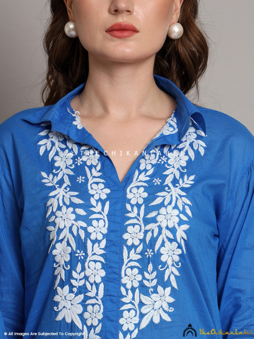 Front view of blue cotton shirt featuring hand-embroidered white motifs