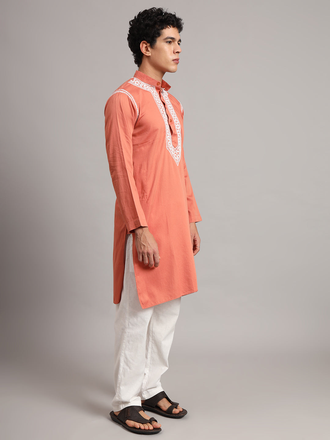 Uman Mens Kurta featuring floral embroidery bordered by fine decorative threadwork around the chest placket, balanced by a simple body and full-length sleeves.