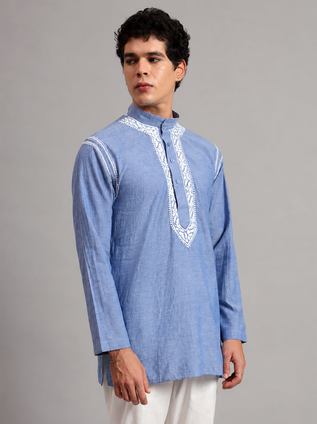 Denim men's kurta with a mandarin collar and four visible front buttons, framed by floral Chikankari embroidery extending from the neckline towards the waist.