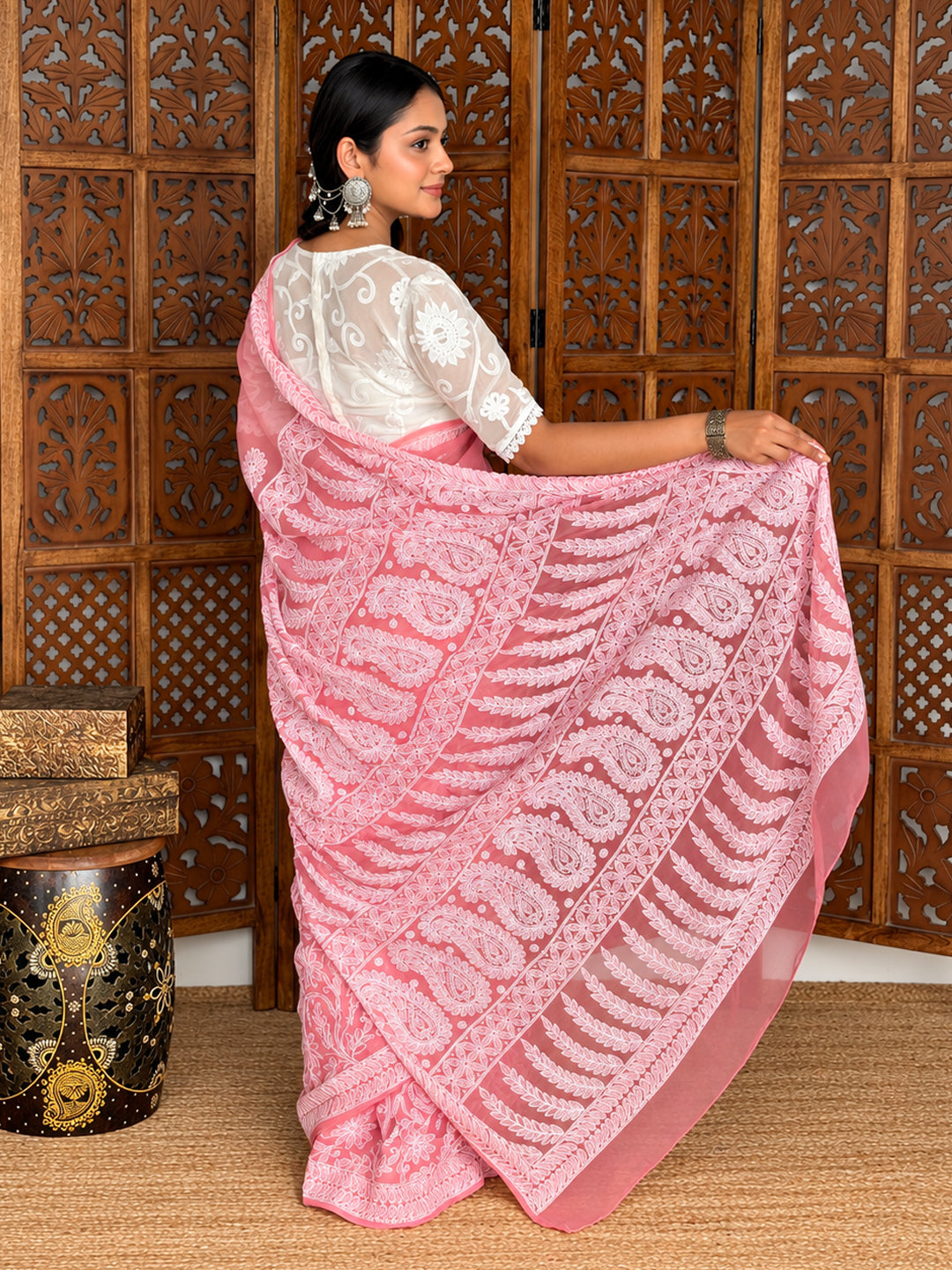 Model showcasing the Kiana Georgette Chikankari Saree with one hand holding the pallu at her waist, revealing the embroidered fabric and border.