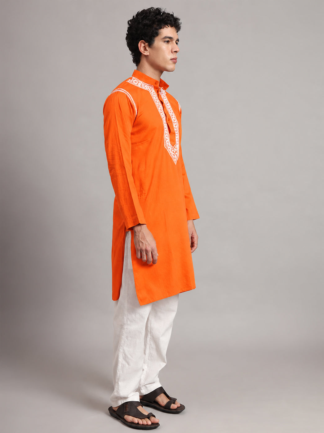 Modelled Uman men's kurta with a straight body, side slits and long sleeves, featuring concentrated Chikankari detailing around the mandarin collar and upper chest.