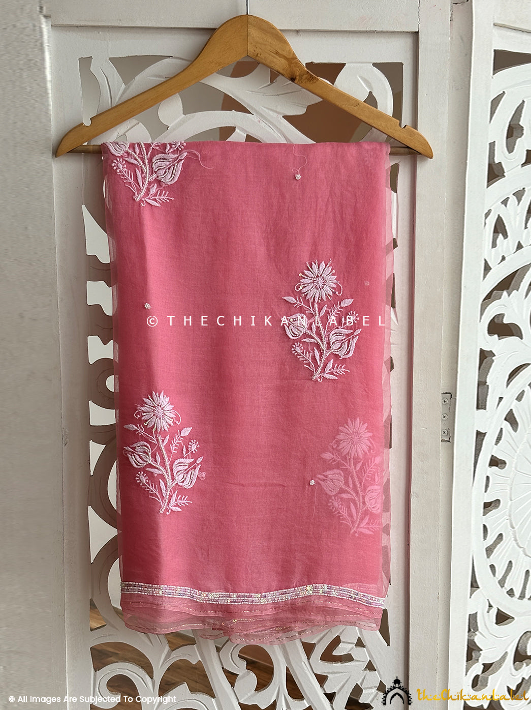 Artistic shot of an organza chikankari pearl work saree showcasing delicate floral motifs, handcrafted embroidery, and pearl craftsmanship suitable for celebratory occasions.