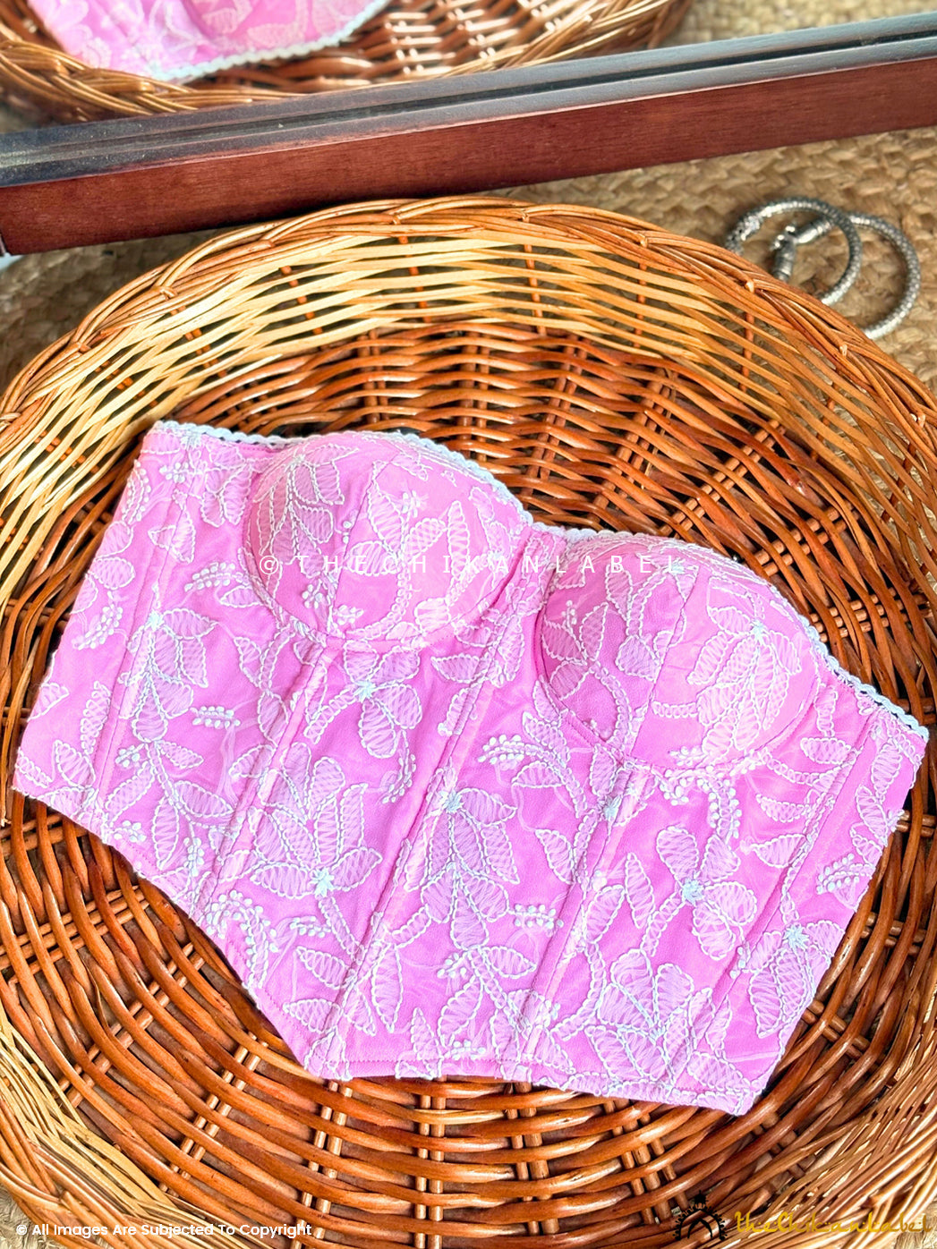 Strapless embroidered corset top for women paired with high-waisted trousers.