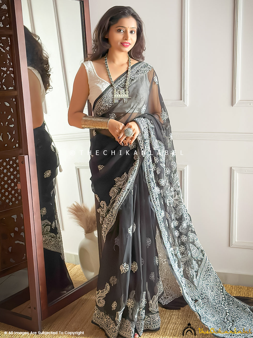 Woman wearing premium georgette chikankari saree with intricate hand embroidery and delicate resham threadwork, styled with ethnic silver jewelry and modern blouse design.