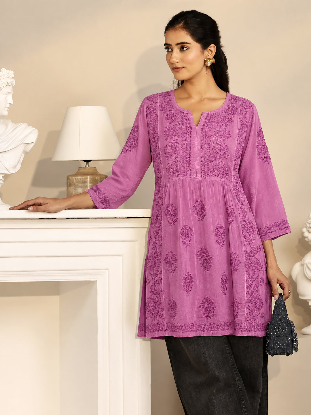 Women's short Chikankari kurti with embroidered floral patterns extending from the shoulders to the hem, combining traditional Indian embroidery with contemporary ethnic fashion.