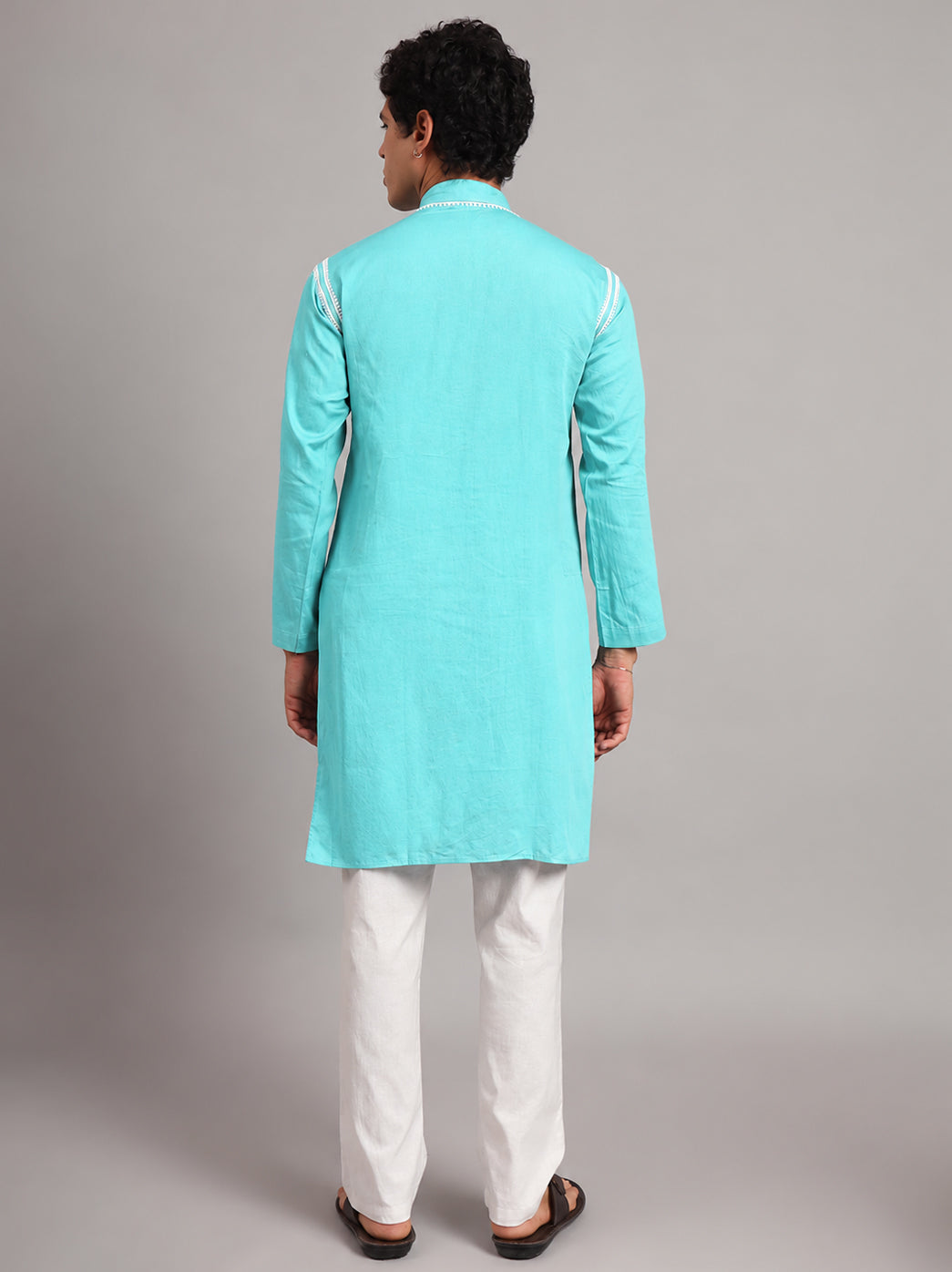 Men's Uman Chikankari kurta featuring a mandarin collar, full sleeves and narrow embroidered shoulder accents, styled with straight trousers and open-toe sandals.