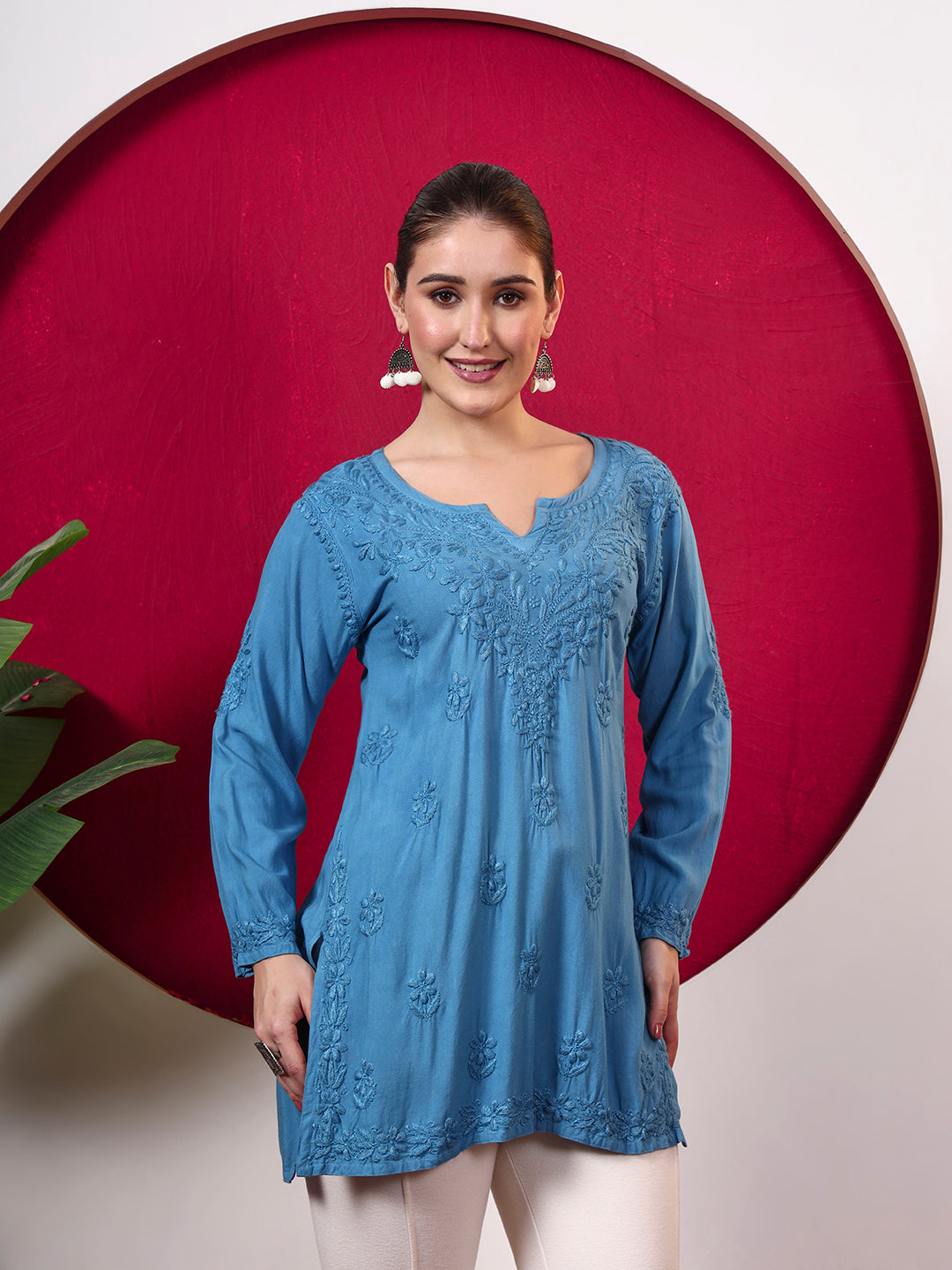Female model wearing the Shruti Rayon Short Kurti featuring detailed Chikankari embroidery, full sleeves, a notched neckline and a relaxed silhouette for comfortable everyday wear.