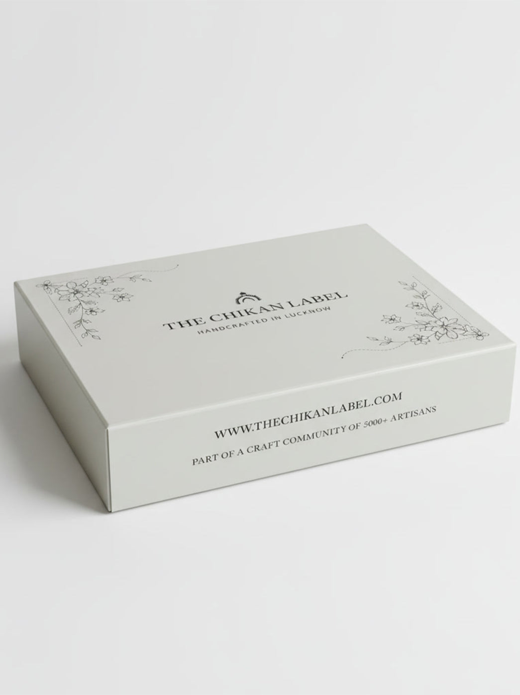The Chikan Label premium gift box with floral artwork at opposite corners of the lid and “Handcrafted in Lucknow” printed beneath the brand name.
