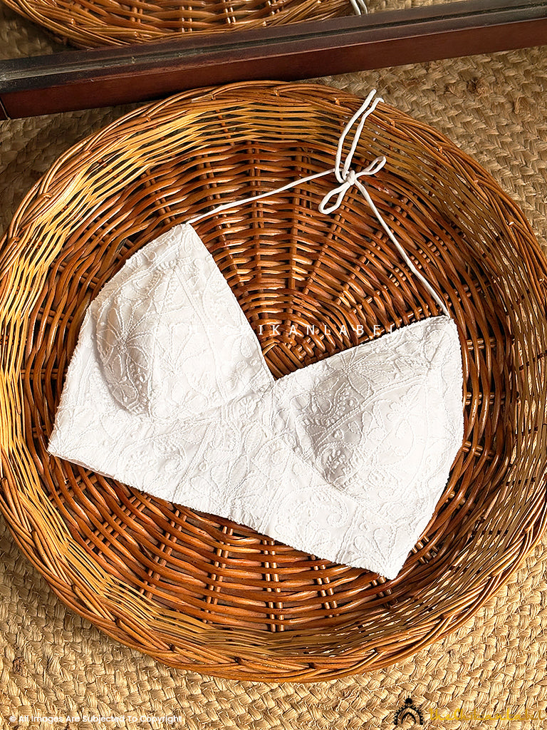 Hand-embroidered sleeveless viscose chikankari blouse displayed on a wicker basket for ethnic wear styling