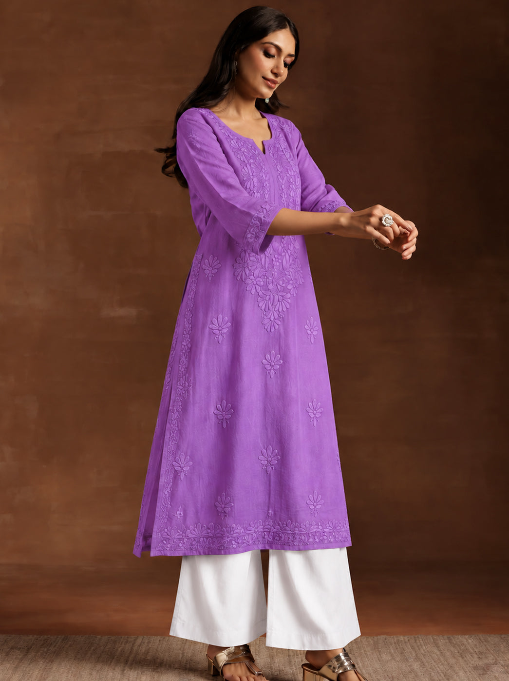 Woman wearing a trending straight kurti crafted from lightweight rayon fabric with traditional Chikankari embroidery and three-quarter sleeves.