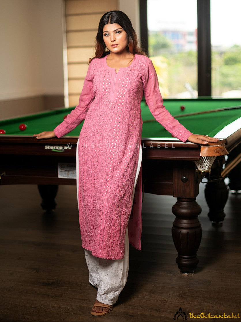 Woman wearing ice cream pink chikankari kurti standing by a pool table