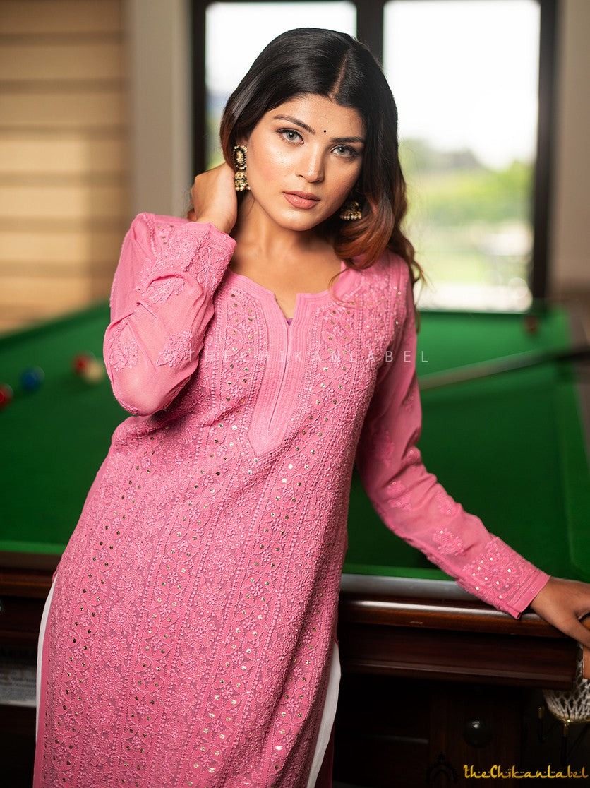 Model leaning against a pool table wearing ice cream pink chikankari kurti with white palazzos, styled for a casual indoor look.
