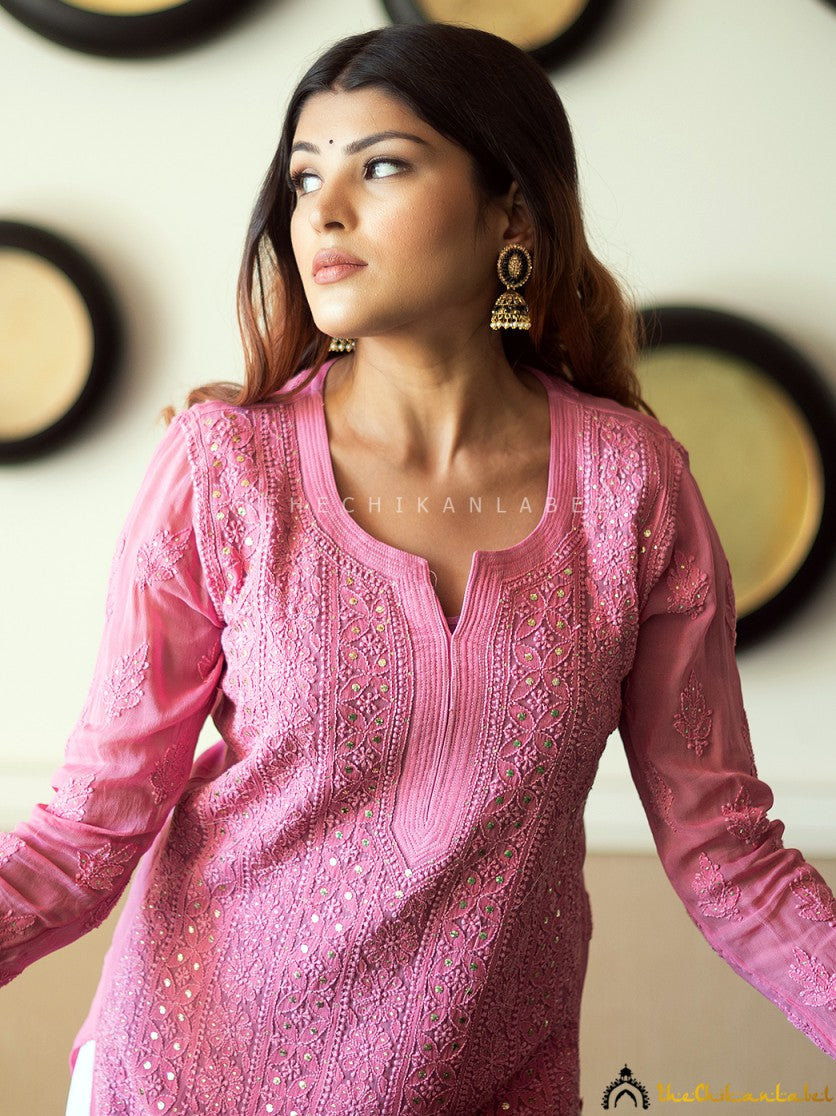 Full-body view of woman in pastel pink straight chikankari kurti paired with white bottoms, showcasing elegant and relaxed ethnic style.