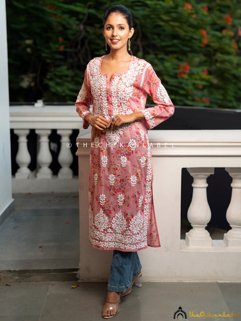 Woman wearing a pink mulmul cotton chikankari kurti with hand-embroidered white floral patterns.