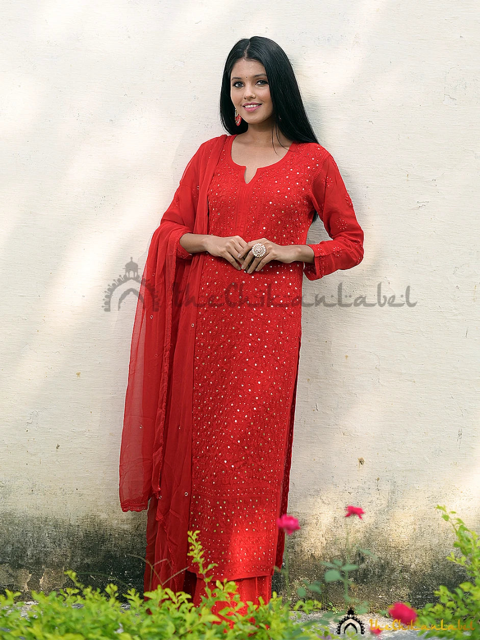 Front view of model wearing red chikankari kurta set with mirror embroidery and matching dupatta.