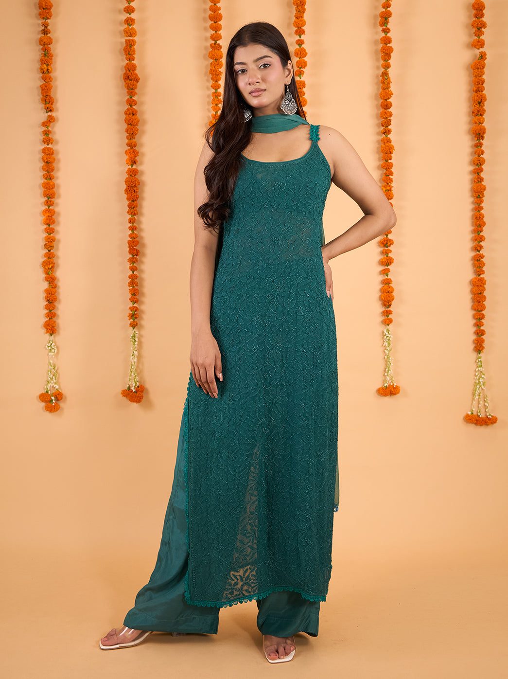 Model wearing a viscose Chikankari strappy kurta set with a sheer dupatta around the neck and one end falling beside the embroidered kurti.