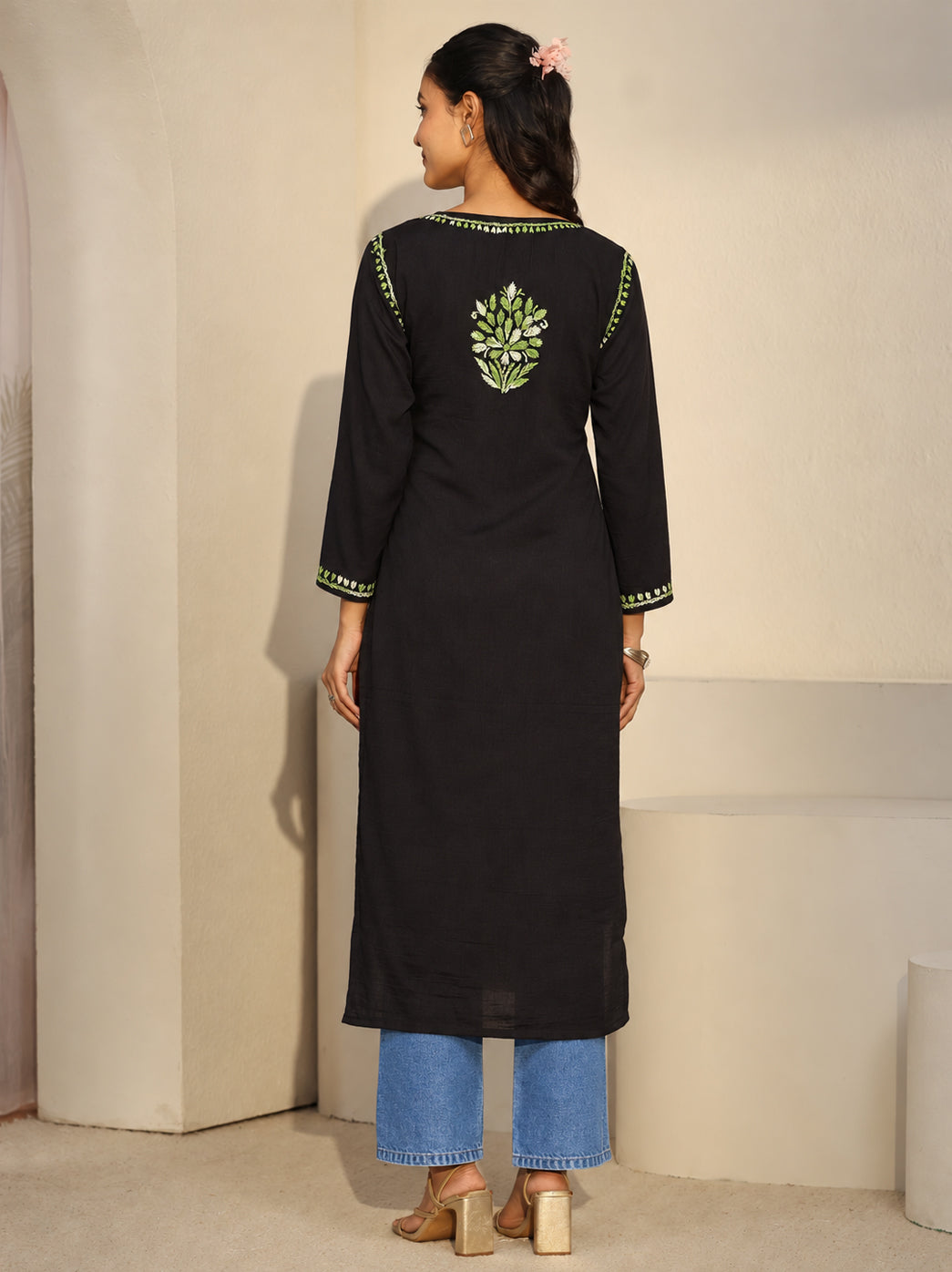 Model showcasing an embroidered rayon Chikankari kurti with a rounded neckline, small central slit and three-quarter sleeves, accessorised with earrings, a bracelet and rings.