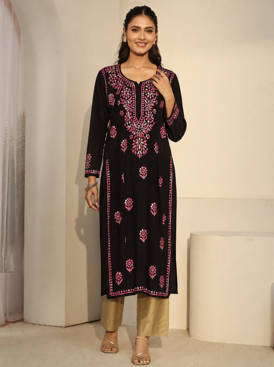 Model wearing the Ayra Rayon Straight Kurti by The Chikan Label, featuring floral Chikankari embroidery, a rounded slit neckline and three-quarter sleeves, styled with wide-leg jeans and strappy sandals.