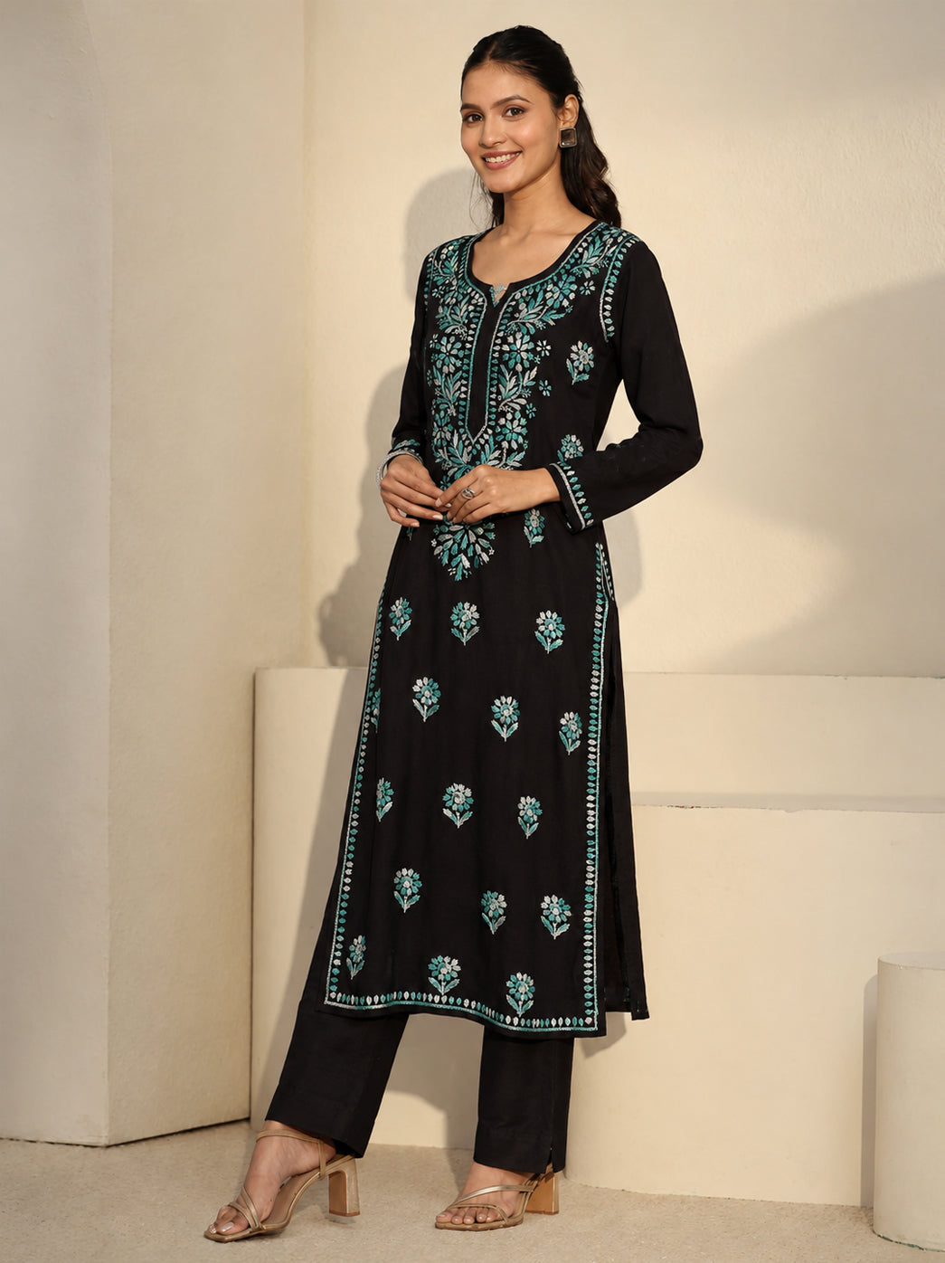 Full-length fashion photograph of a model in the Ayra Rayon Straight Kurti, highlighting its three-quarter sleeves, rounded slit neckline, side openings and floral Chikankari detailing.