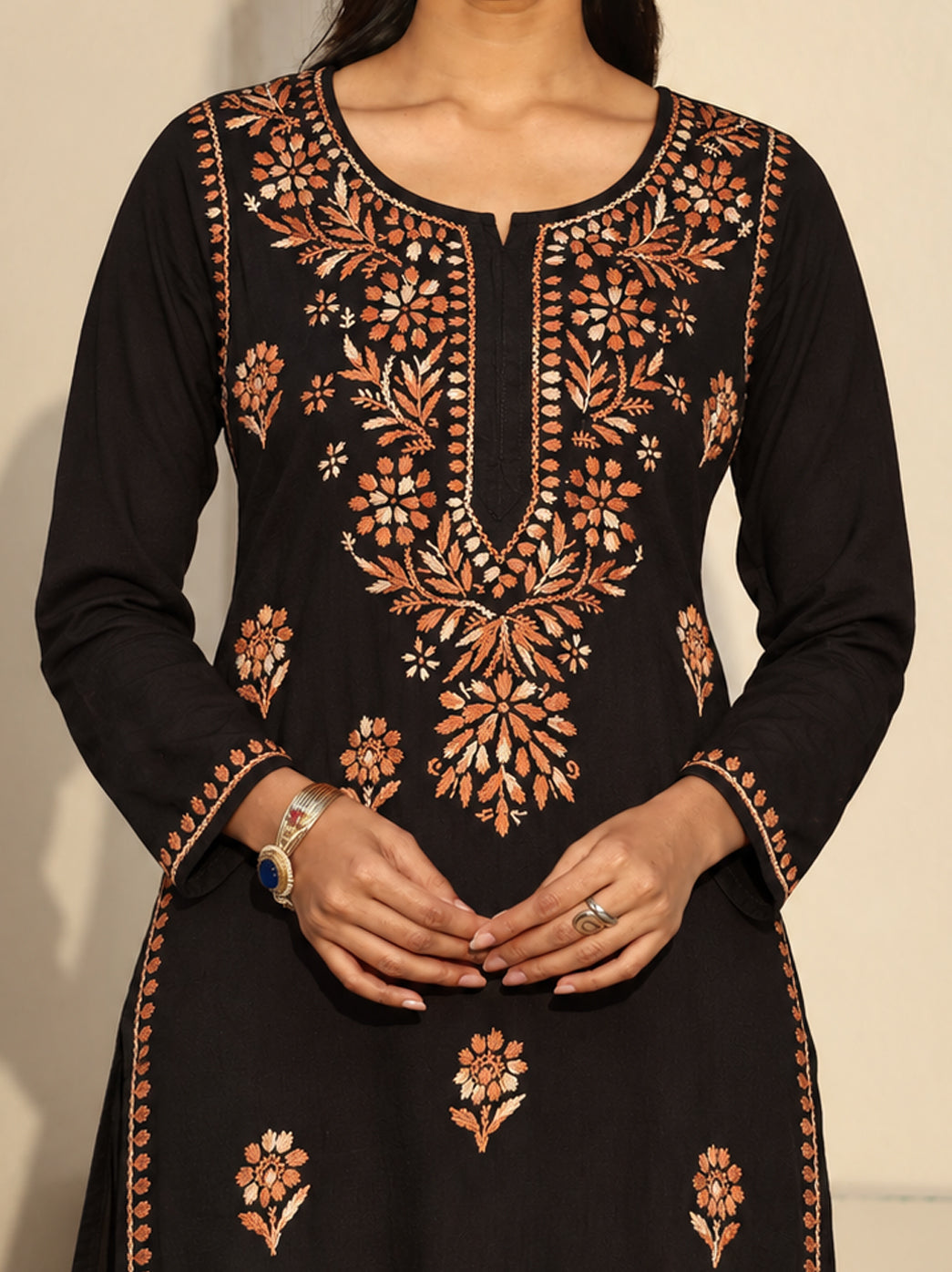 Model showcasing an embroidered rayon Chikankari kurti with a rounded neckline, small central slit and three-quarter sleeves, accessorised with earrings, a bracelet and rings.