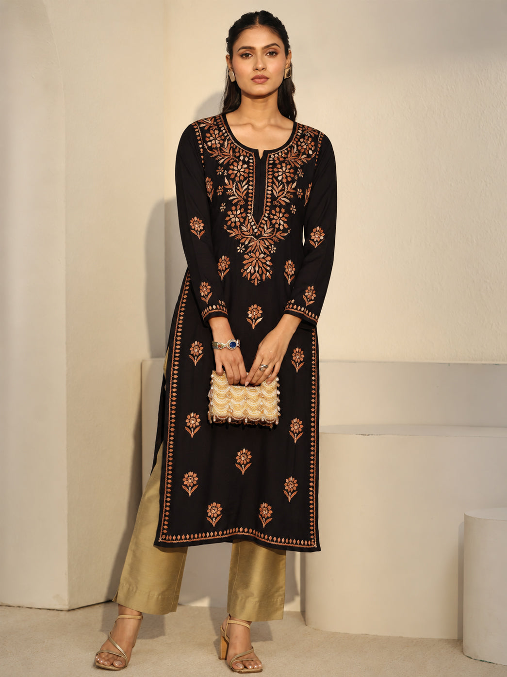 Ayra Rayon Straight Kurti shown on a model standing with her hands together, highlighting the long straight silhouette, side slits and detailed Chikankari embroidery across the front.