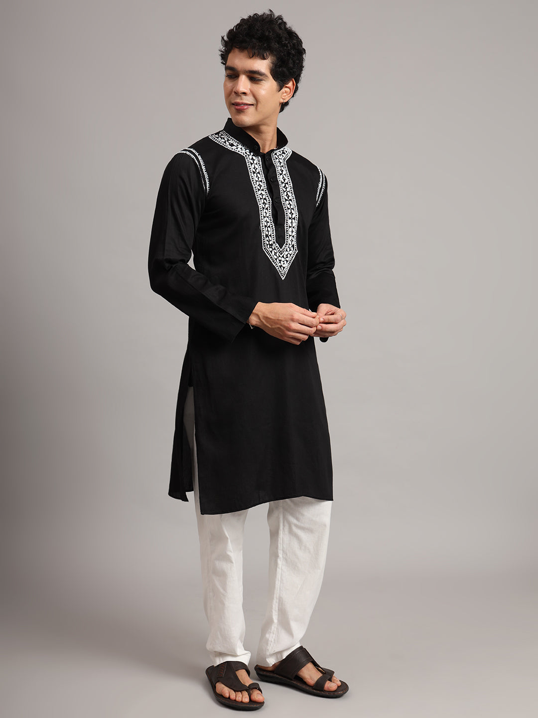 Uman men's Chikankari kurta with a mandarin collar, button fastening and intricate embroidered chest detailing, shown in a full-length outfit with traditional sandals.