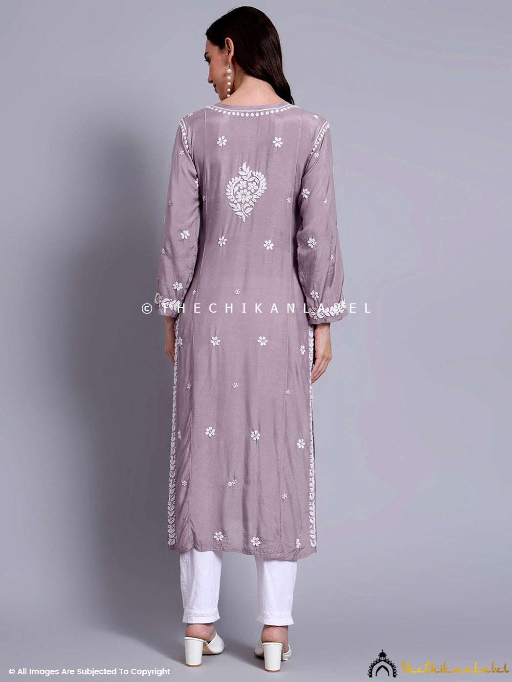Woman styling a muslin straight kurti with chikankari work paired with minimal jewelry and ethnic flats.

