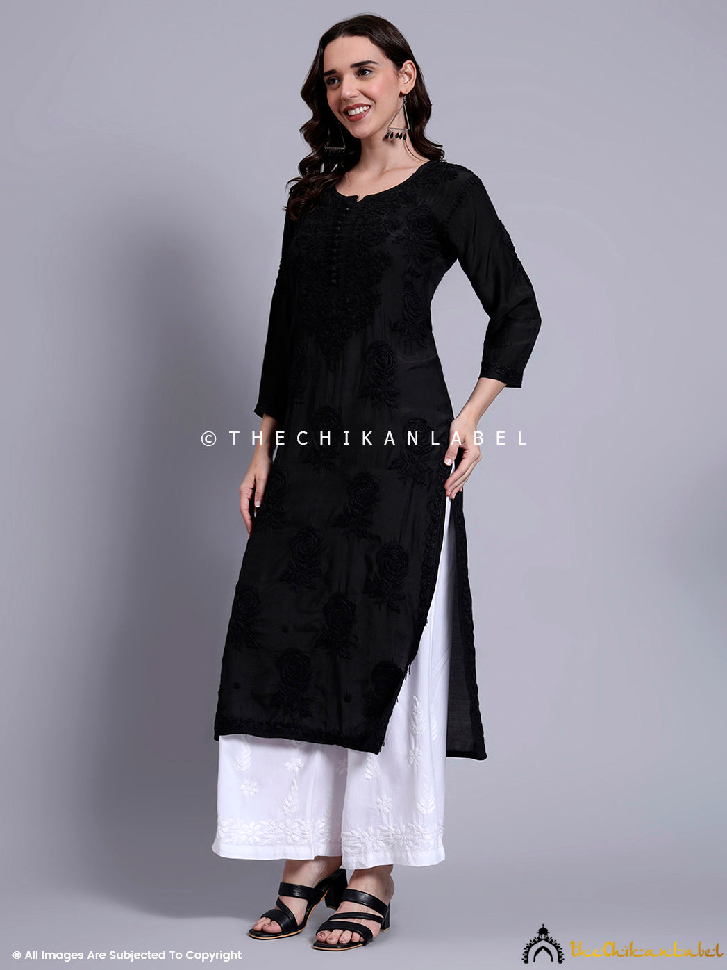 Front-facing view of muslin chikankari kurti with detailed floral hand embroidery, paired with white palazzos and black sandals.

