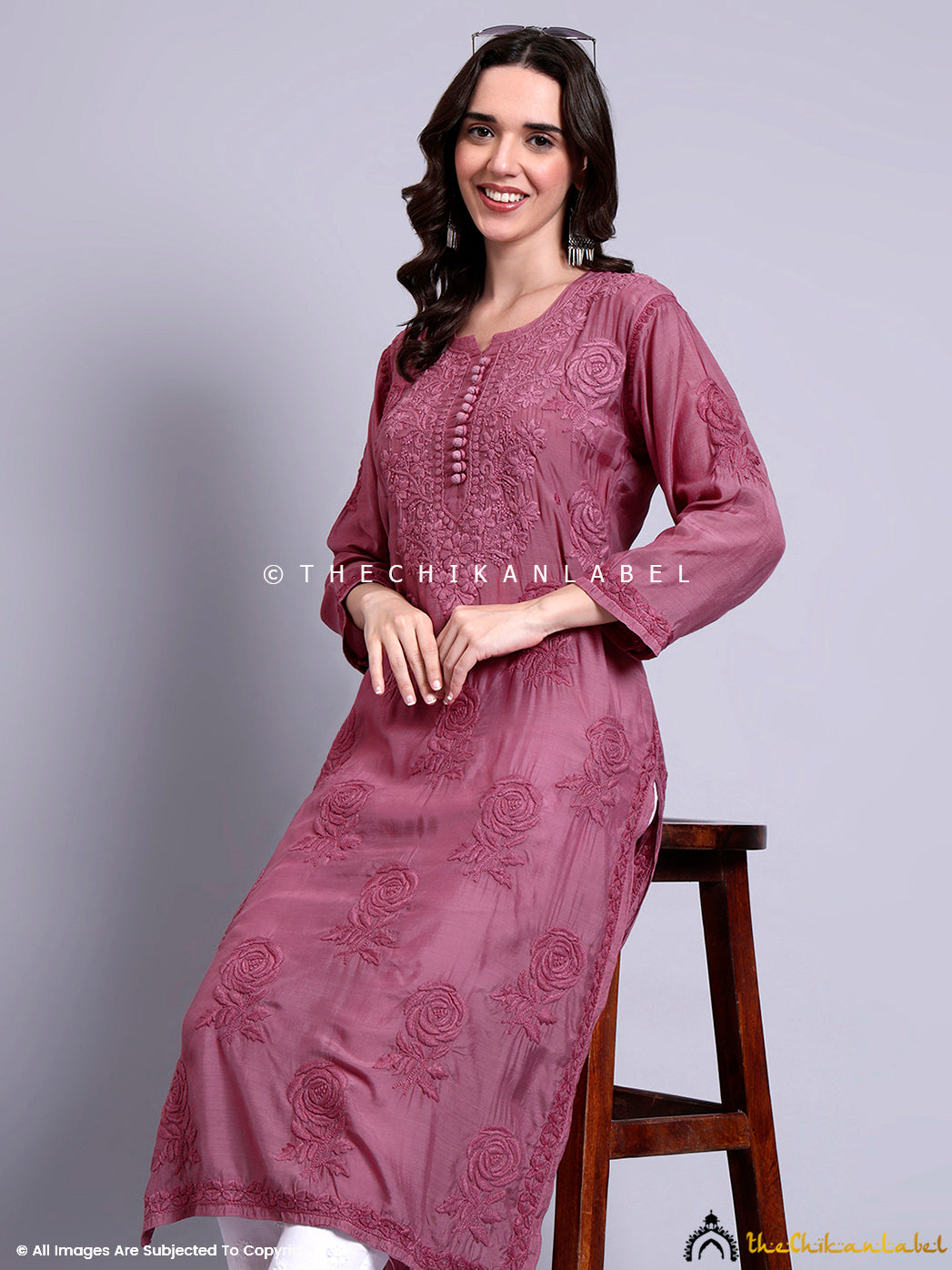 Front-facing view of muslin chikankari kurti with detailed floral hand embroidery, paired with white palazzos and black sandals.

