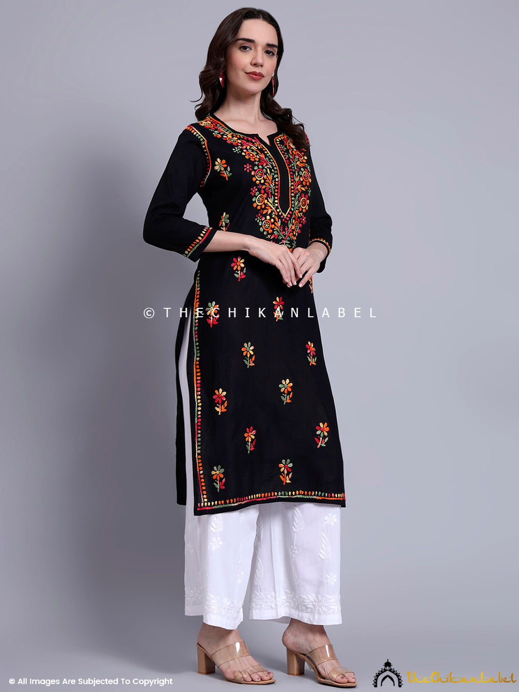Front-facing kurti design with detailed neck embroidery, handcrafted sleeves, and border highlights, styled with statement earrings.


