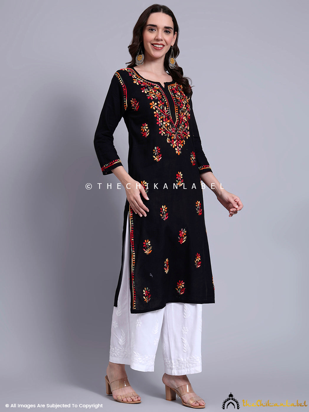Front-facing kurti design with detailed neck embroidery, handcrafted sleeves, and border highlights, styled with statement earrings.

