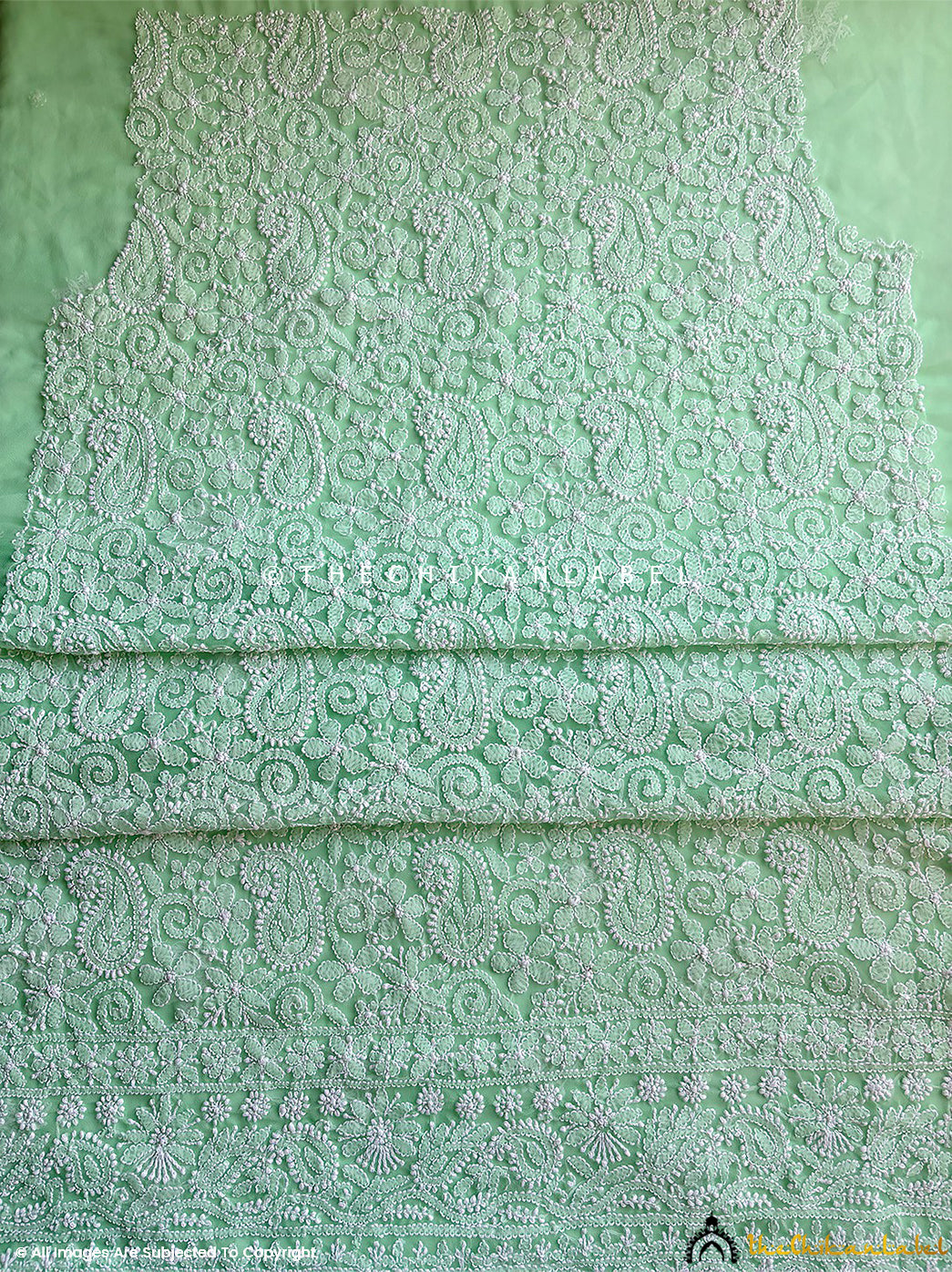 “Close-up of detailed hand-embroidered chikankari work on unstitched georgette suit material with dupatta”