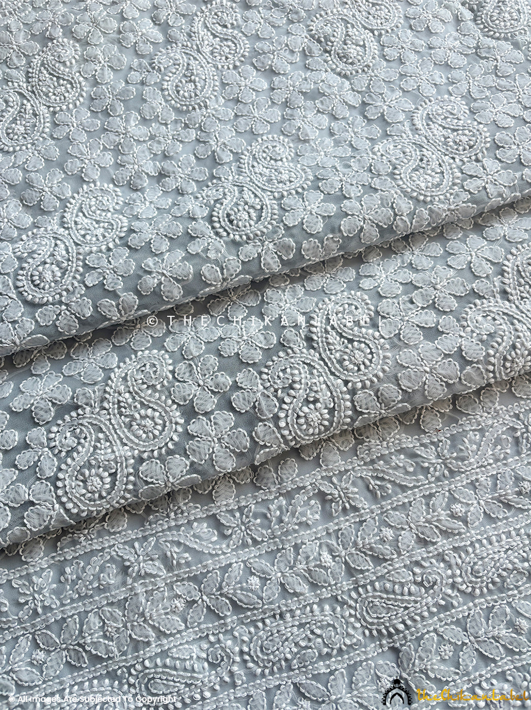 “Close-up of detailed hand-embroidered chikankari work on unstitched georgette suit material with dupatta”