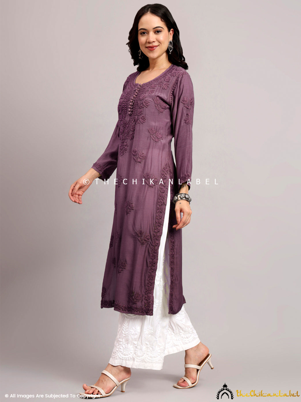 Model showcasing a muslin straight chikankari kurti with heavy embroidery on neckline and scattered motifs across the front panel.

