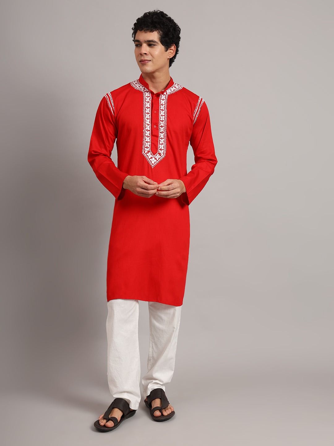 Uman Mens Kurta shown on a standing model, with floral Chikankari embroidery surrounding the button placket and extending into a pointed panel below the chest.