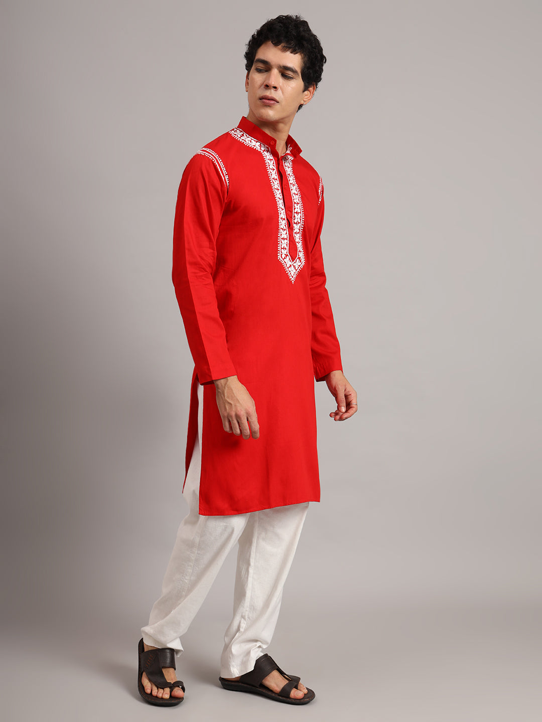 Model wearing the Uman men's kurta with hands loosely joined at the waist, displaying embroidered collar borders and leafy motifs arranged along the chest panel.