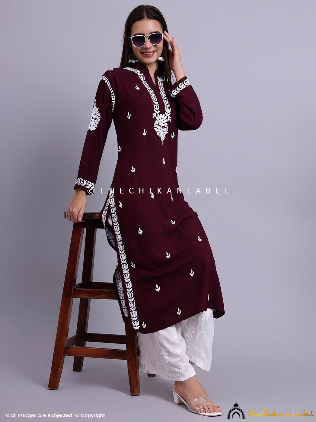 Front-facing image of a woman wearing a mandarin collar chikankari straight kurti paired with embroidered bottoms.

