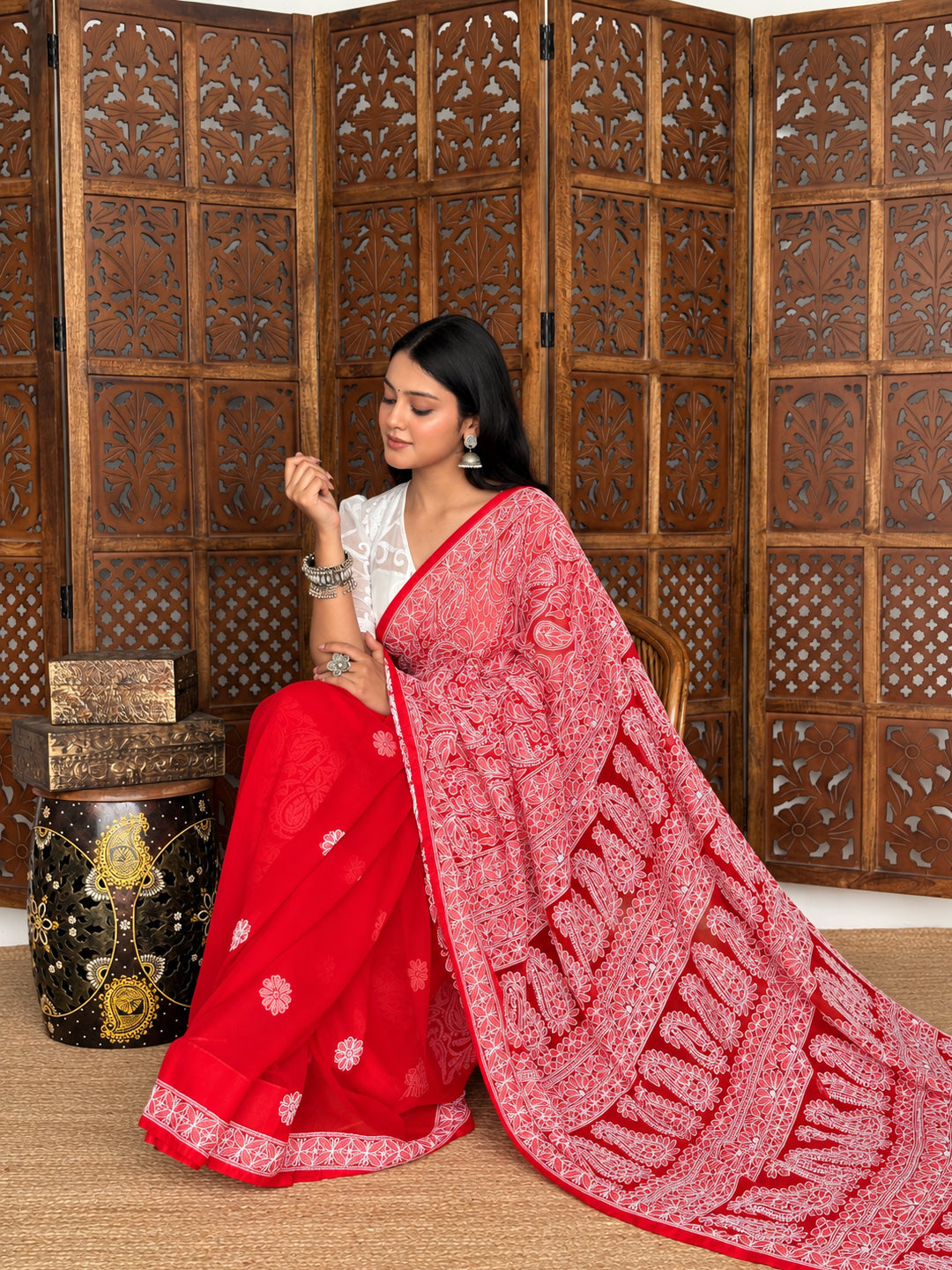 Model holding the draped fabric of the Sahira Chikankari saree at the waist, displaying floral embroidery across the front and an extended ornamental pallu.