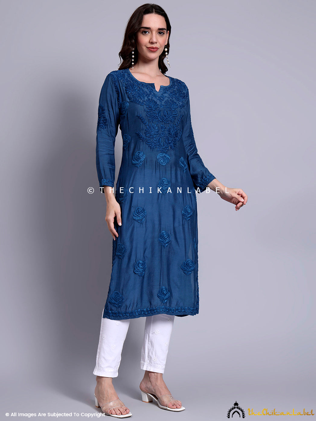 Model dressed in premium muslin chikankari straight kurti with rose motifs, paired with minimal jewelry and sheer heels for a graceful ethnic look.


