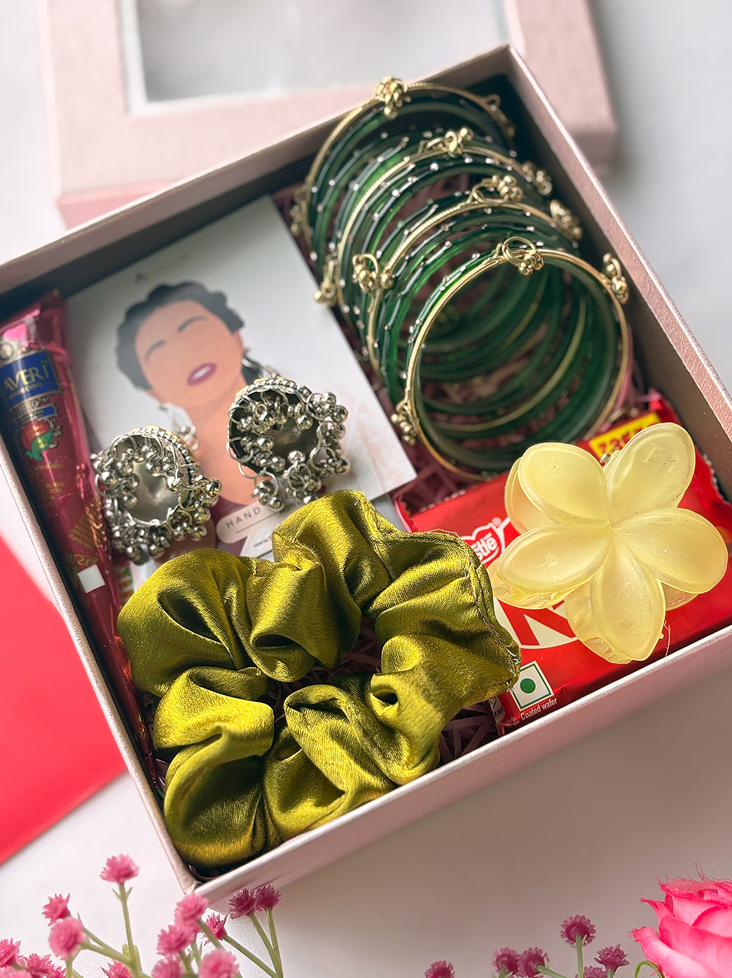 Women’s festive gift hamper with bangles set, oxidised earrings, satin scrunchie, flower-shaped claw clip, mehndi cone, bindi and chocolate.