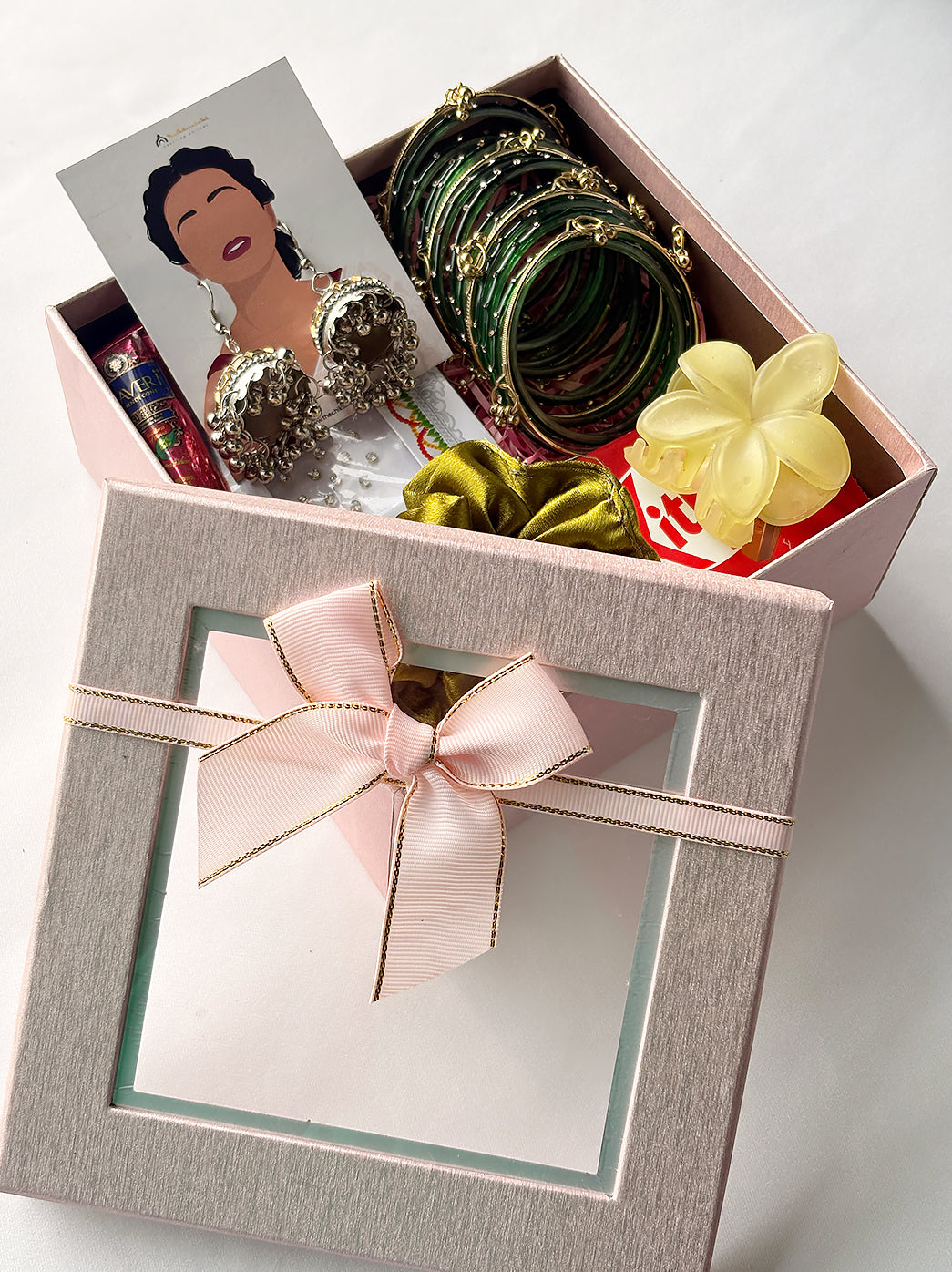 Ready-to-gift Sawan hamper for women with decorative bangles, statement earrings, scrunchie, claw clip, mehndi cone, bindi and chocolate.