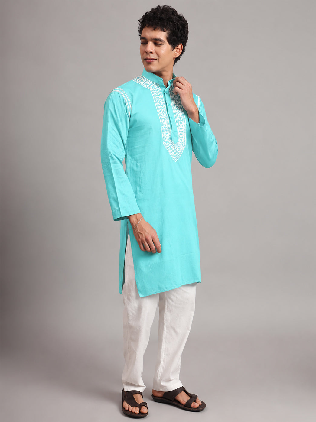Uman Mens Kurta displaying an elongated embroidered neckline panel, small front buttons and shoulder detailing, with the model holding his hands together at waist level.