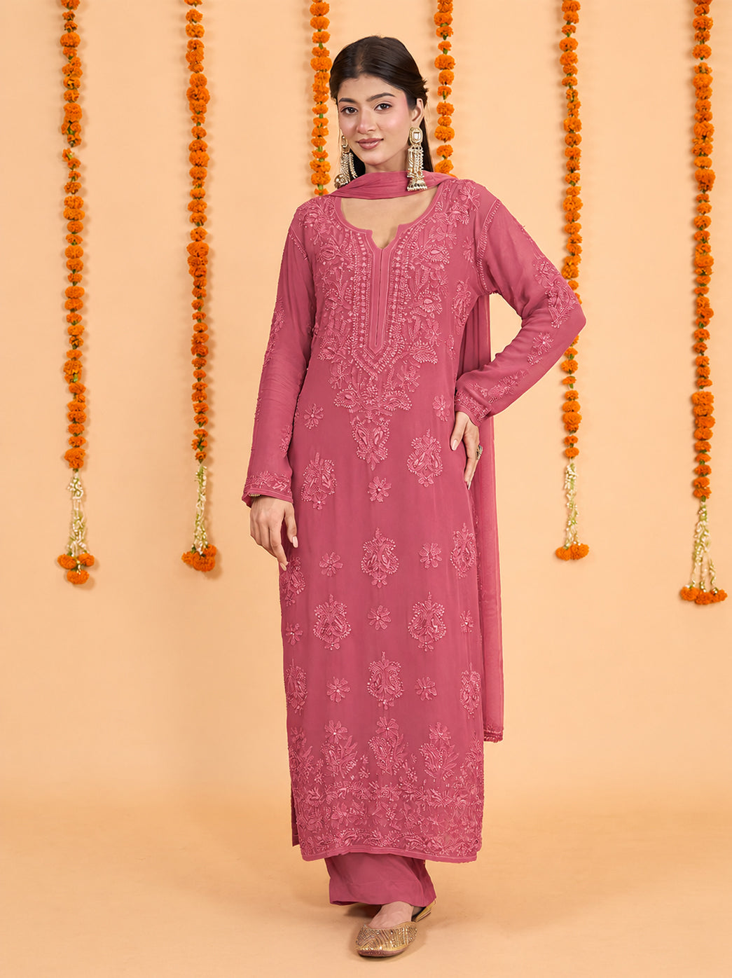Model wearing the Shahana Viscose Straight Kurti Palazzo Set with Dupatta, featuring floral and paisley Chikankari embroidery, full sleeves and a detailed hem against a marigold backdrop.