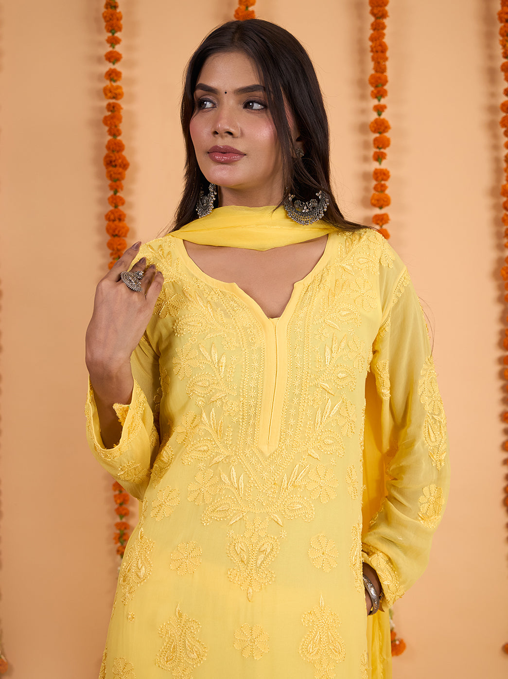 Shahana Chikankari kurta set photographed against a warm studio backdrop, with tonal floral motifs, full sleeves and a coordinating dupatta completing the ensemble.