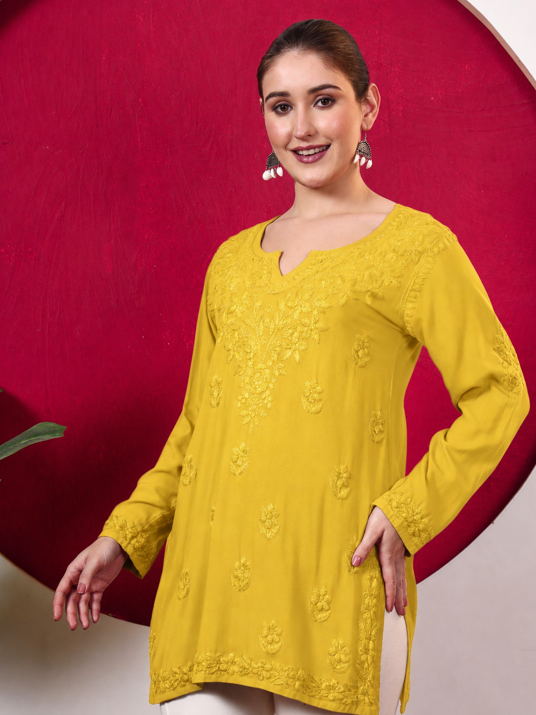 Female model wearing the Shruti Rayon Short Kurti featuring detailed Chikankari embroidery, full sleeves, a notched neckline and a relaxed silhouette for comfortable everyday wear.