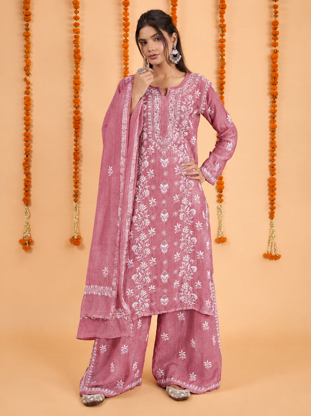 Model wearing the Sofia Mul Chanderi Chikankari Kurta Set with Dupatta, featuring a straight kurta with floral embroidery, wide-leg trousers and an embroidered dupatta against a marigold backdrop.