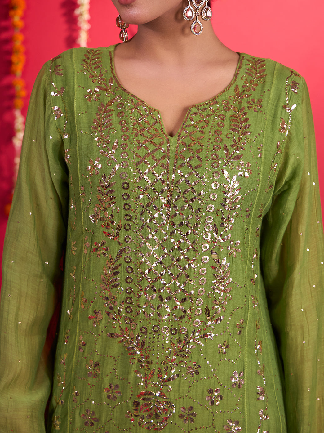 Tehzeeb Mul Chanderi Chikankari kurta set shown in a full-length model photograph, highlighting floral embroidery, shimmering embellishments and decorative edging along the kurta hem.