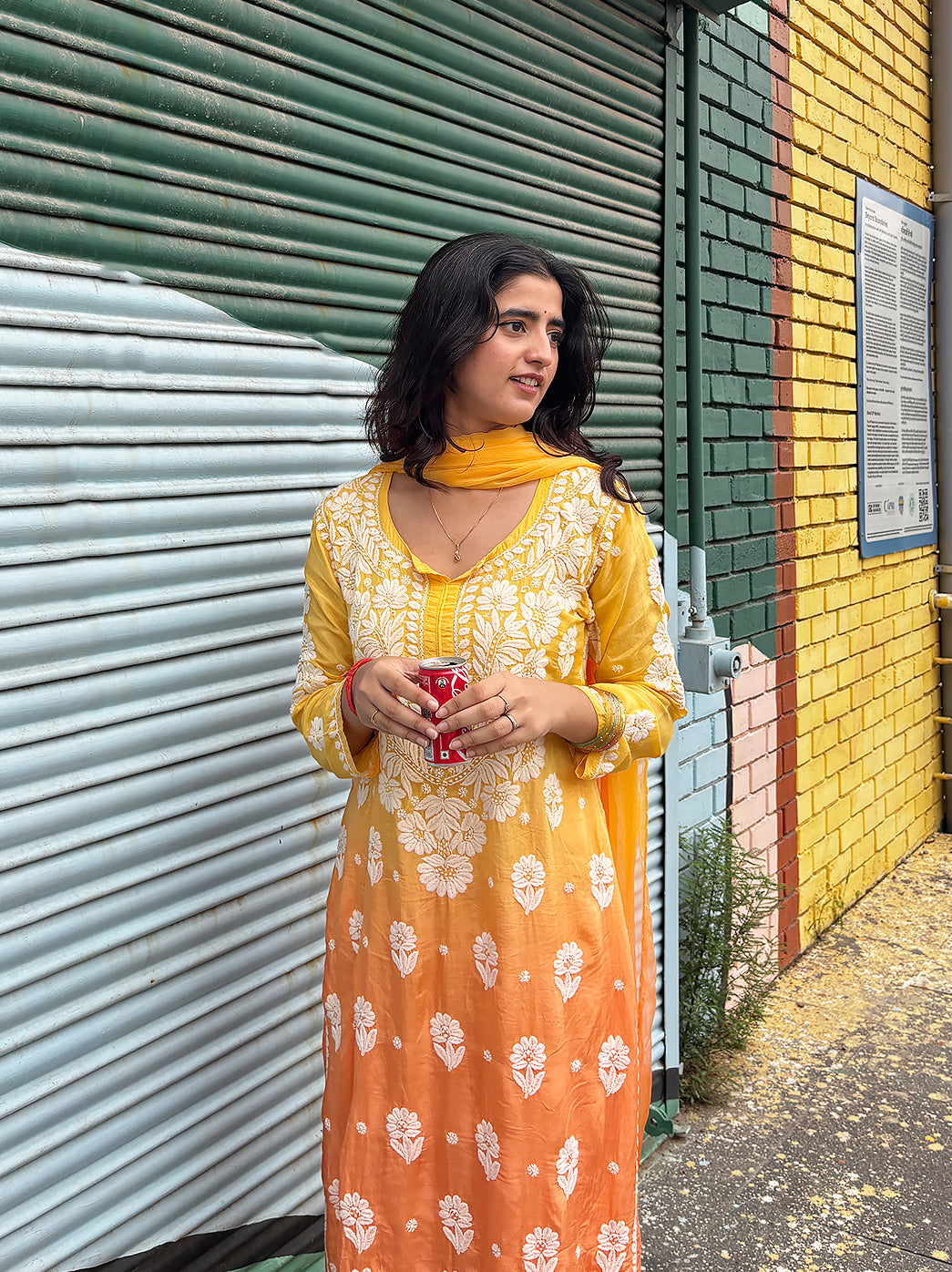 Woman posing in a trending Chikankari kurta set with dense embroidery on the bodice and hem, scattered floral motifs and coordinated ethnic accessories.