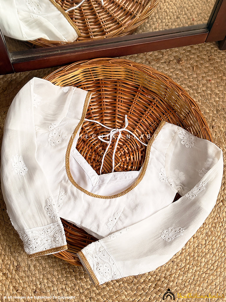 Flat lay of long sleeve chikankari blouse showcasing handcrafted floral embroidery and delicate gold piping.

